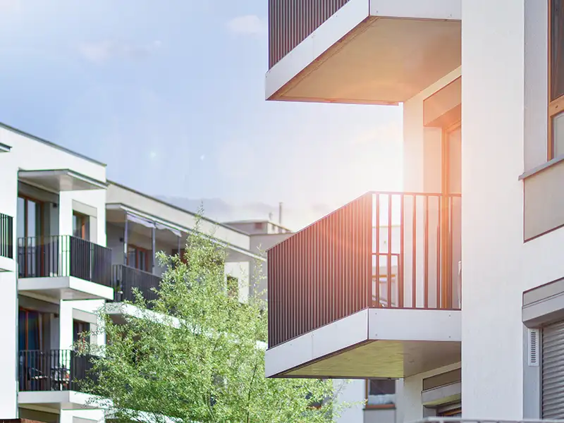 Seher Startbild Unternehmen mobil: modernes Wohnquartier mit Balkonen, Bäumen und Himmel